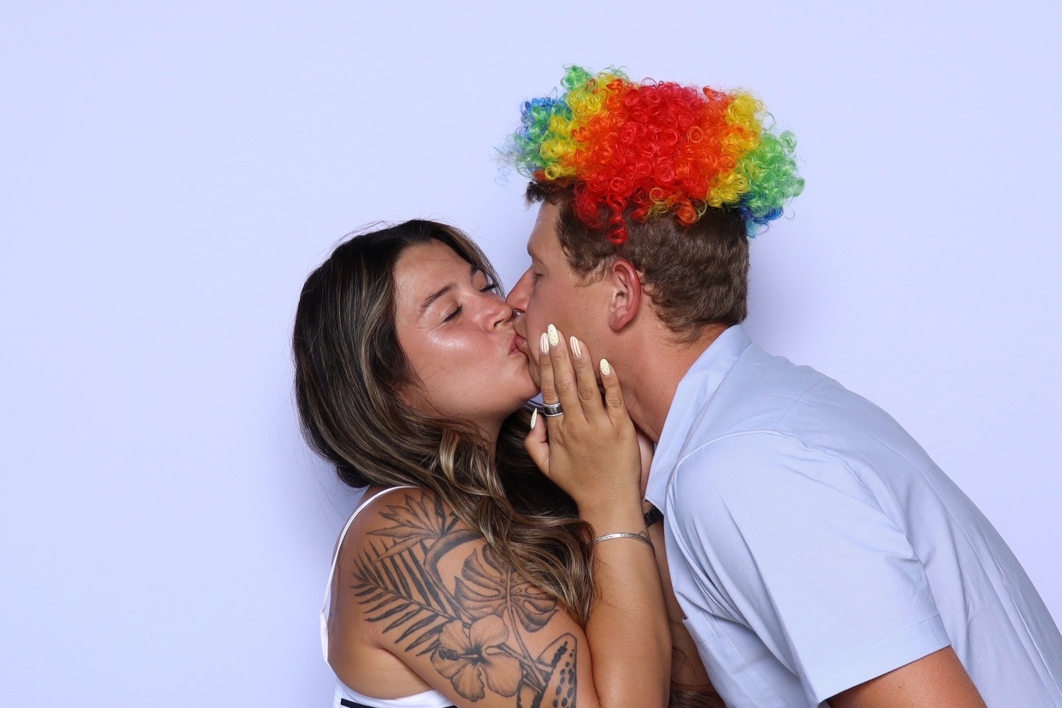 Two guests kissing in the booth, one wearing a rainbow wig
