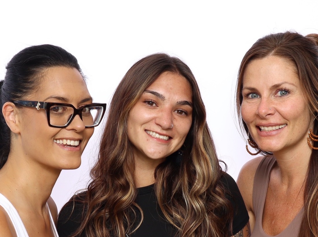 Three guests posing together in front of the booth backdrop
