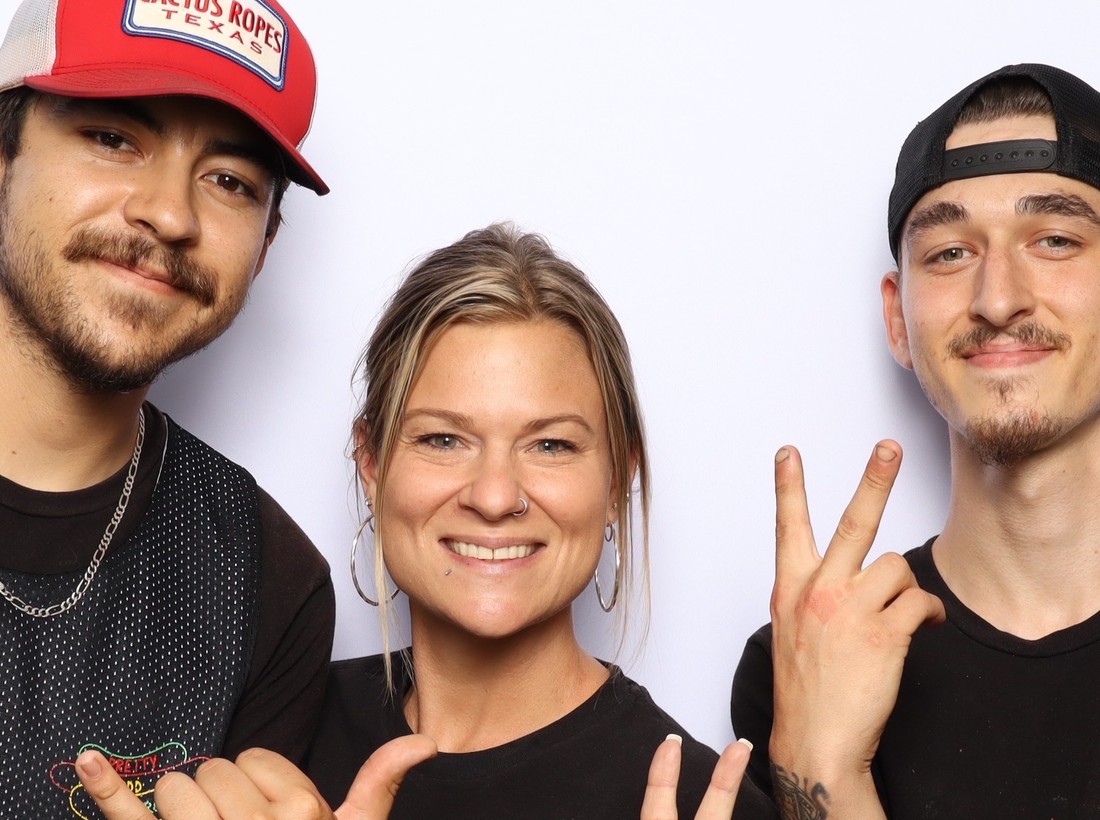 Three guests in matching branded shirts posing together in the booth
