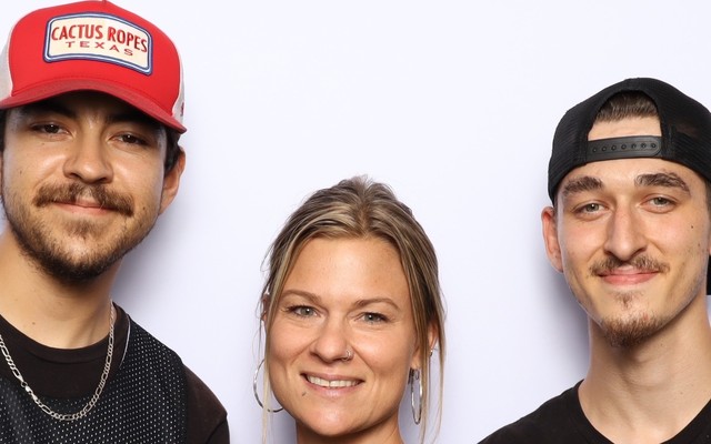 Three guests in matching branded shirts in front of the booth backdrop