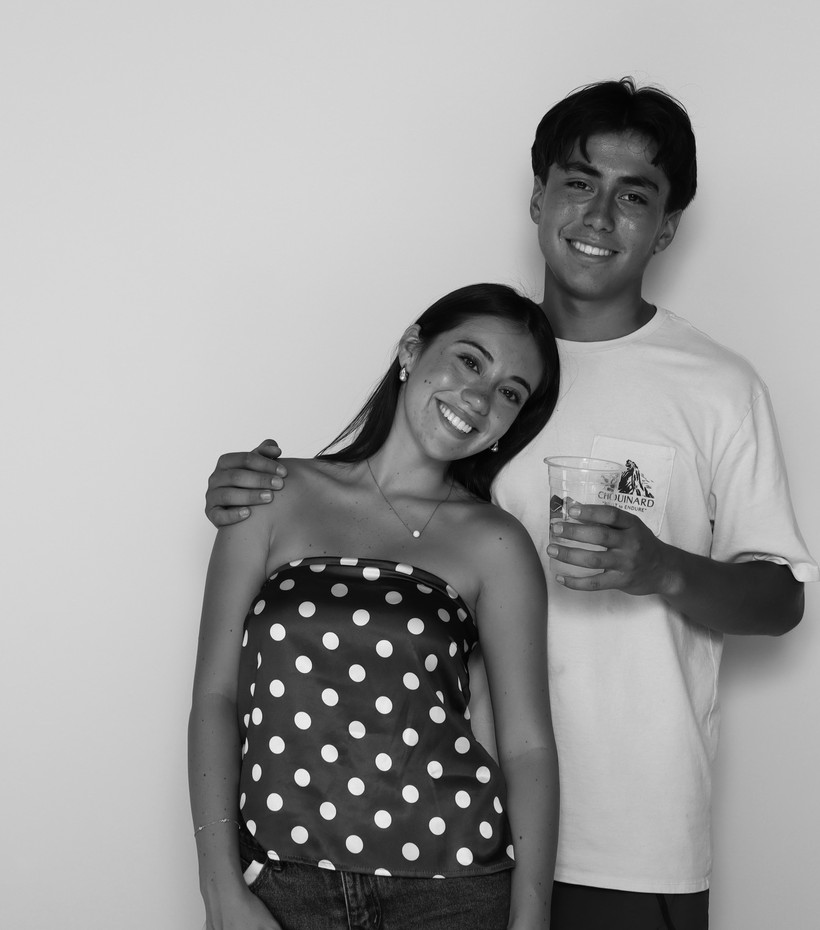 Two guests posing together in front of the booth backdrop