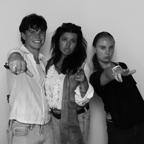 Black-and-white shot of three guests posing, one pointing at the camera, one wearing a flower lei and scarf
