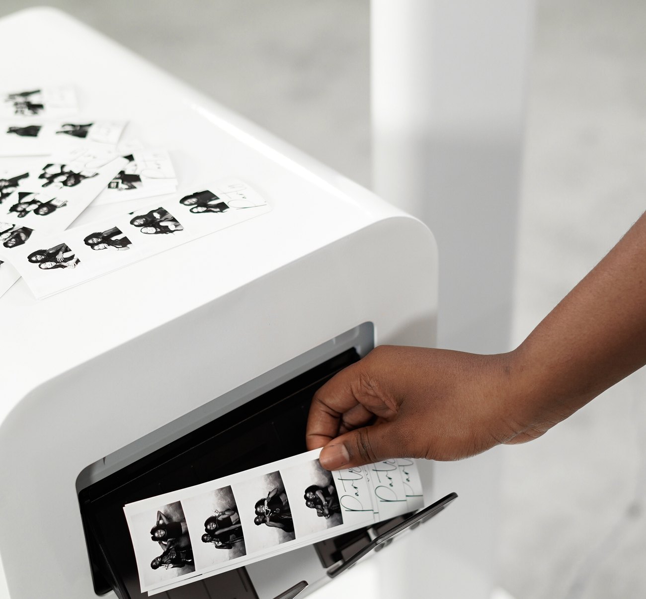 A guest taking a freshly printed photo strip from the booth