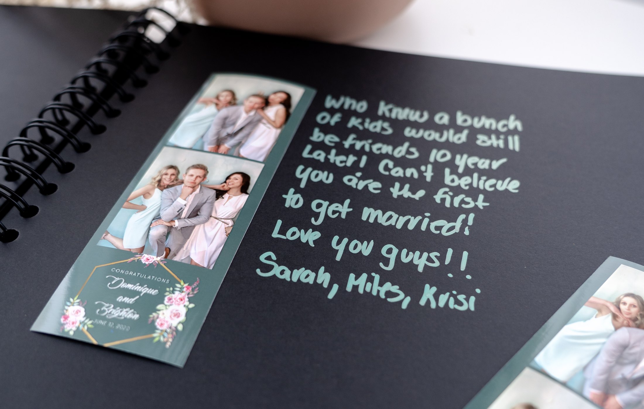 Photo booth strip in a black guestbook beside a handwritten congratulations note in mint ink